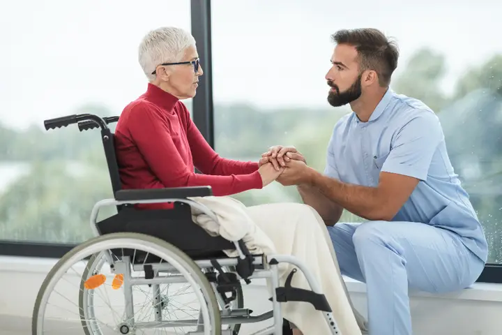Carer talking with an older woman in a wheelchair