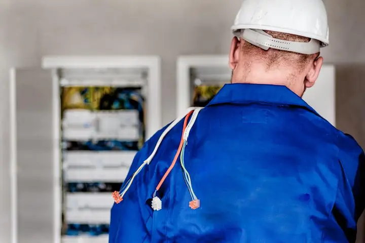 Electrician in a hard hat working at a switchboard